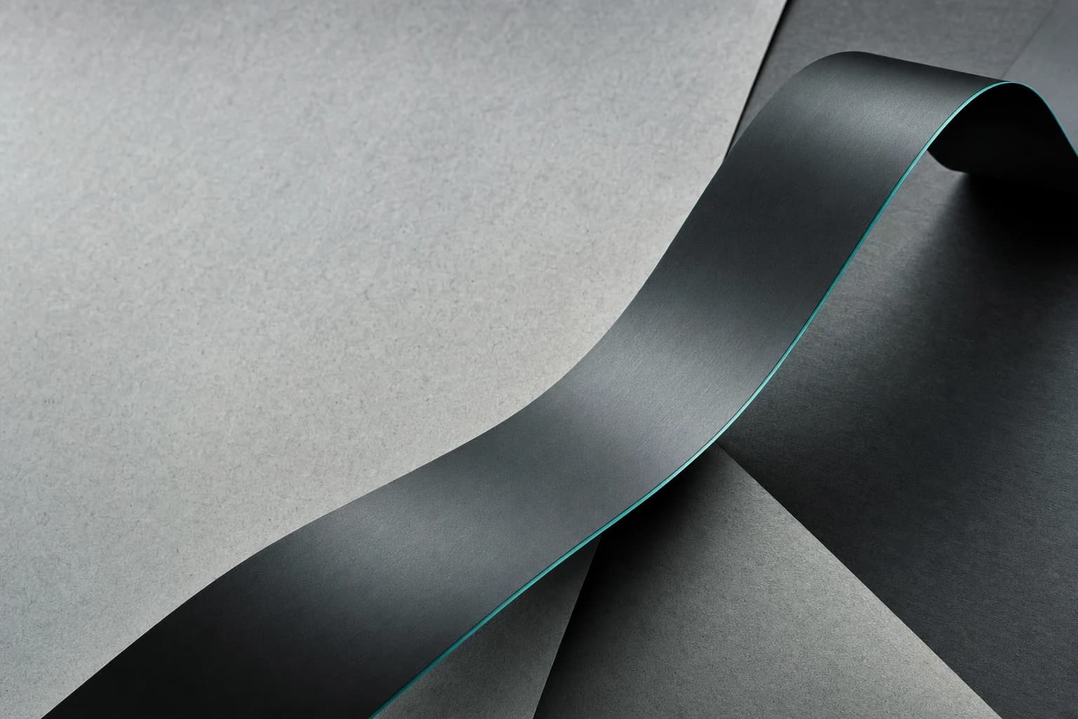 A graphite ribbon crosses a fog-gray surface with a thin teal edge